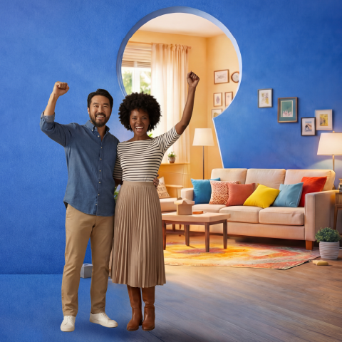 Happy couple celebrating in a living room, representing buying a new home