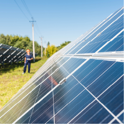 Solar panels installed in a field with a technician inspecting them